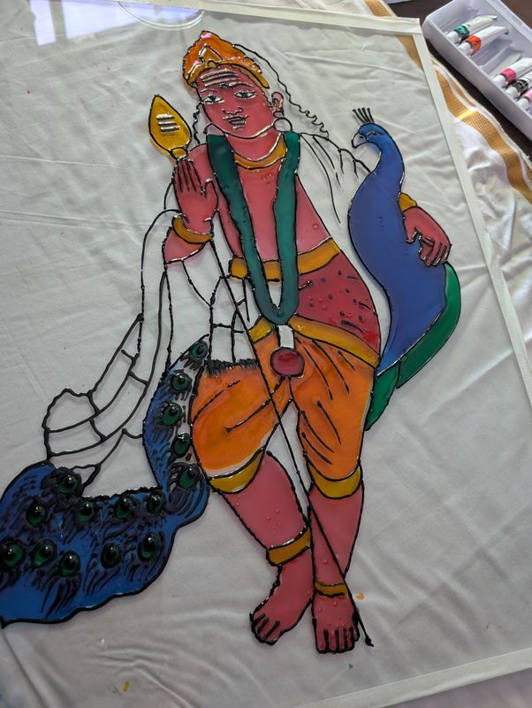 Glass painting in progress of a figure with a peacock